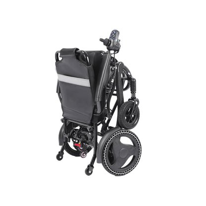 A three-quarter rear view of the Harvey Carbon Power Wheelchair in its folded state. The matte black chair is shown compressed, with the padded black backrest facing forward and featuring a prominent reflective silver strip across its width. All four wheels are compressed and visible, including the textured drive wheels and smaller front casters. The joystick controller on its armrest is visible at the top, and a footplate assembly is folded below. 