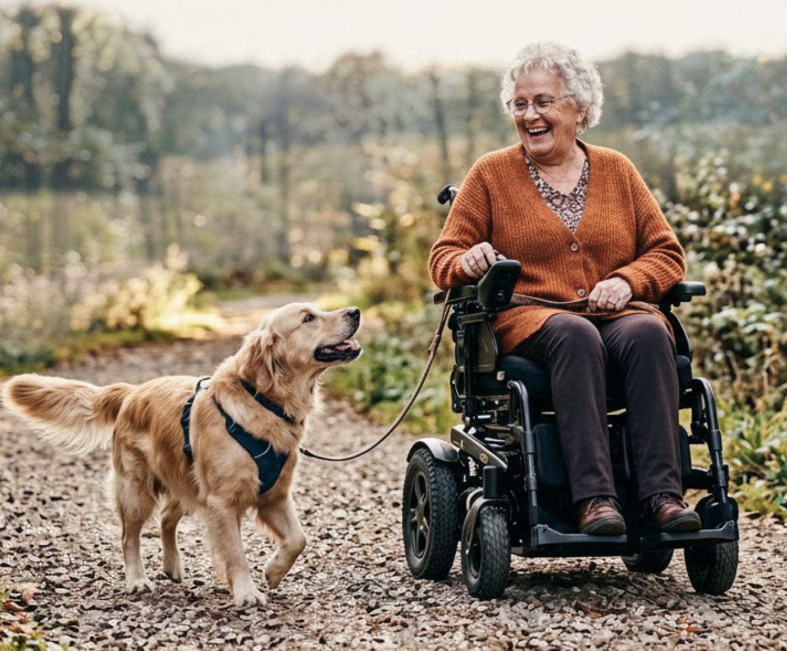 Woman on a Muvon Mobility power wheelchair with a dog on a path in a natural setting